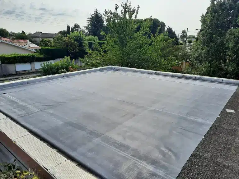 Photo d'un toit plat vue de dessus. Une membrane d'étanchéité est posée pliée sur le toit.